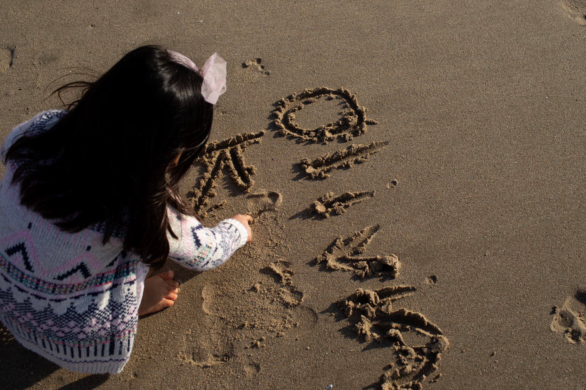 Los Angeles child drawing in sand at beach