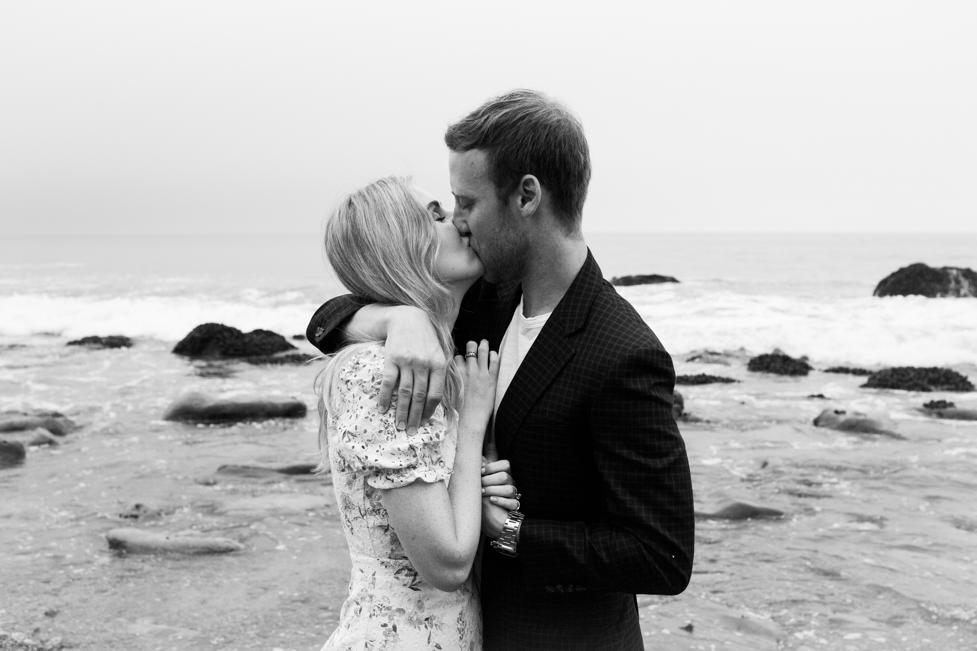 black and white photo couple kissing at beach